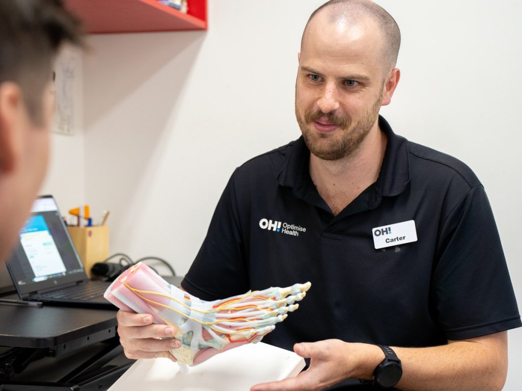 Toowoomba podiatrist explaining plantar fasciitis to a patient using a foot model